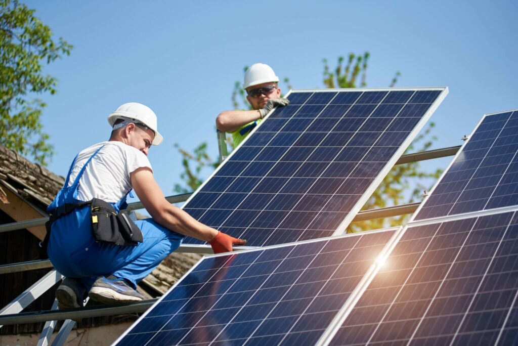 Workers installing solar panels on a house's roof.