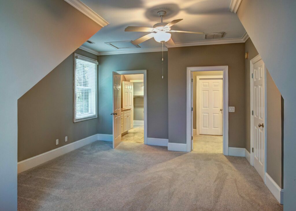 Second floor bedroom with tan walls and doors open to the hallway and bathroom.