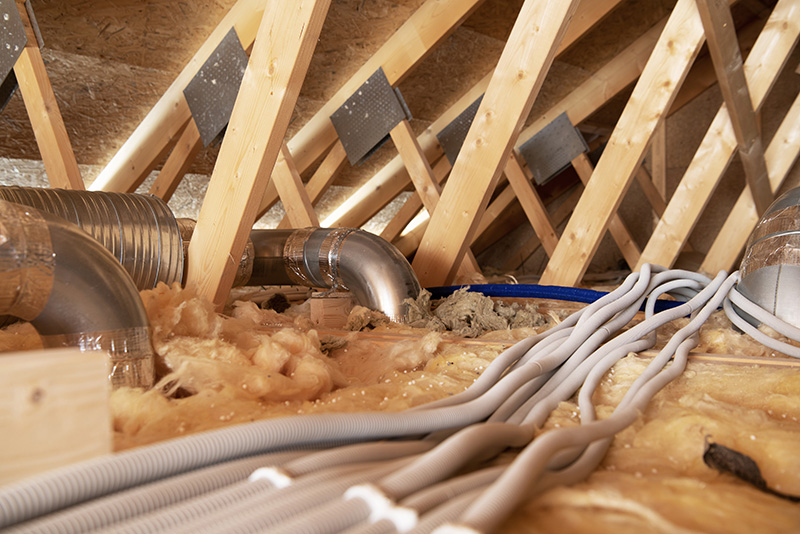 Attic space with various HVAC ducts and tubing.