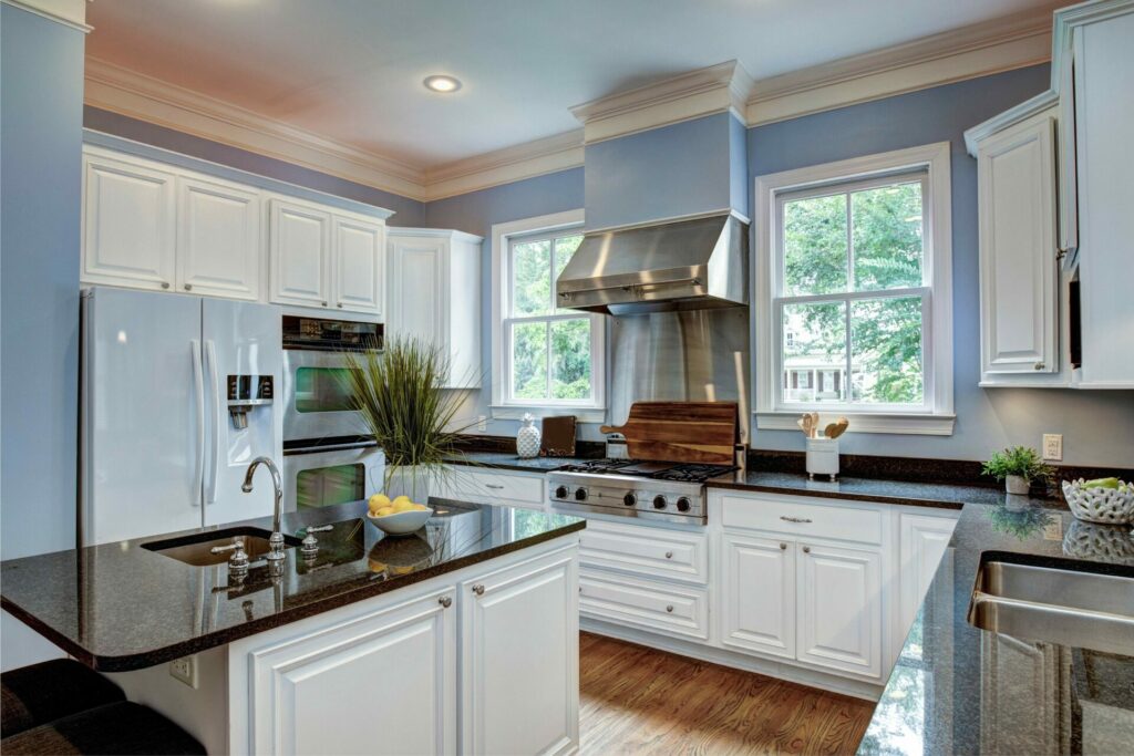 Modern kitchen with island, stainless steel appliances, and white cupboards.